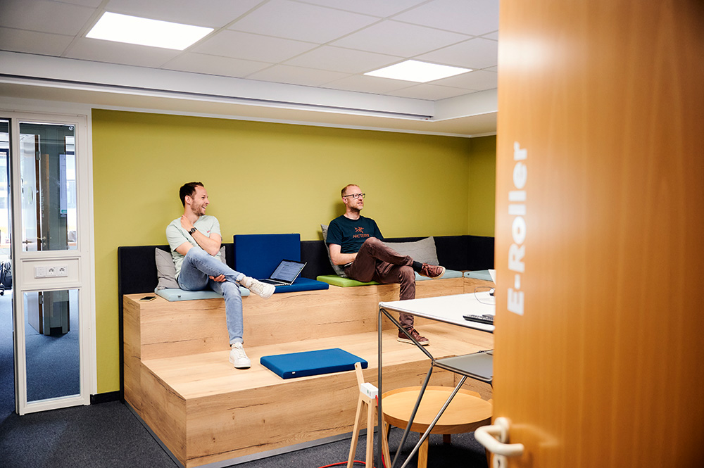 2 Personen sitzen in einem Meeting-Raum.