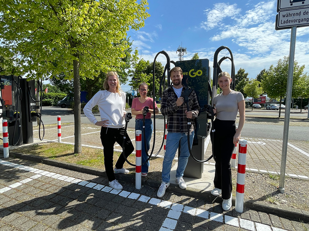 4 Personen stehen vor einer EWE Go-Ladestation.